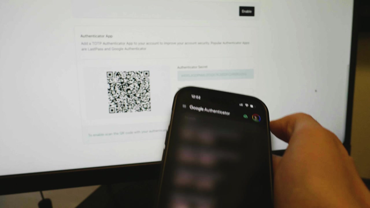 A user scanning the QR code on the screen with their phone's authenticator app.